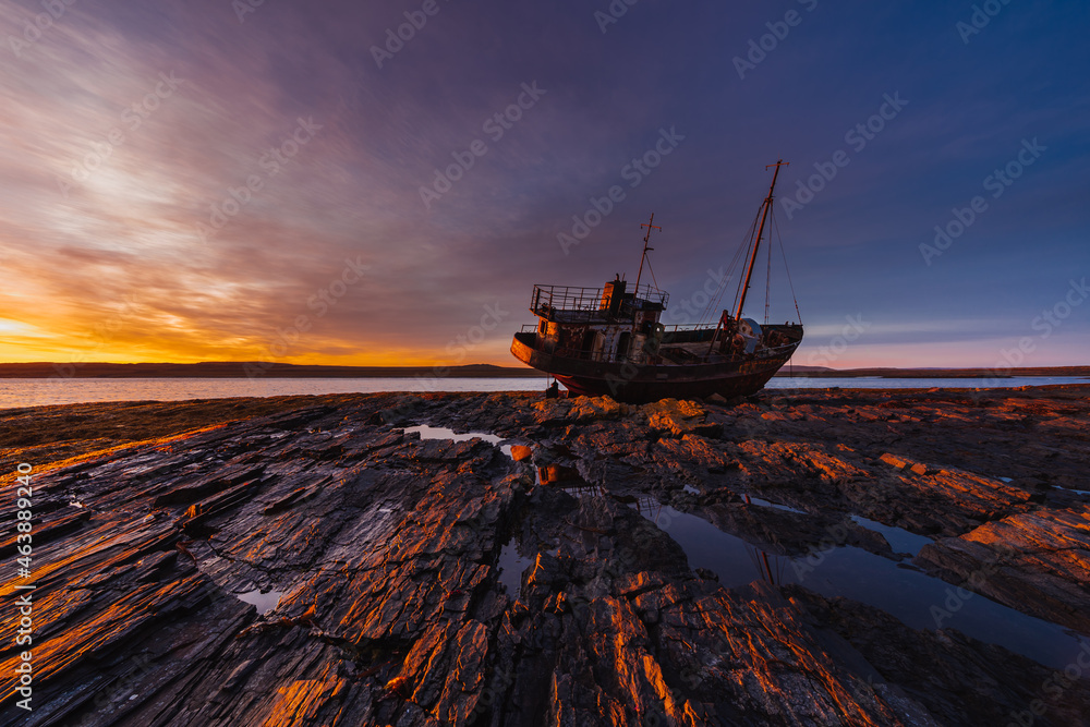 Stranded old fishing schooner at beautiful dawn. The old ship is covered in rust. Rocky coastline of the Barents Sea, Rybachy Peninsula. 