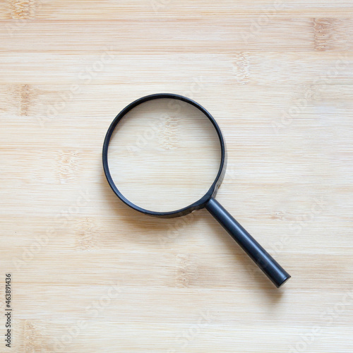 magnifying glass on wood background, flat lay minimal style