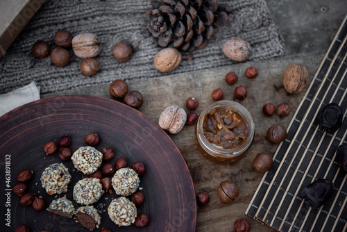 Vegan chocolate truffles on the brown dish with nuts. Top view. Close-up. Copy space. Soft focus. Wooden background.