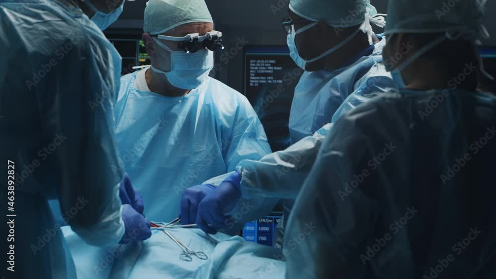 Multiracial team of professional medical surgeons performs the surgical operation in a modern hospital. Doctors are working to save the patient. Medicine, health, cardiology and transplantation. Multiracial team of professional medical surgeons performs the surgical operation in a modern hospital. Doctors are working to save the patient. Medicine, health, cardiology and transplantation.
