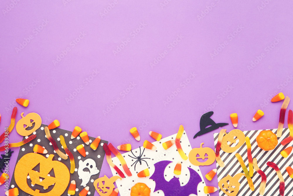 Halloween candies with paper pumpkins, ghost and spider on purple background