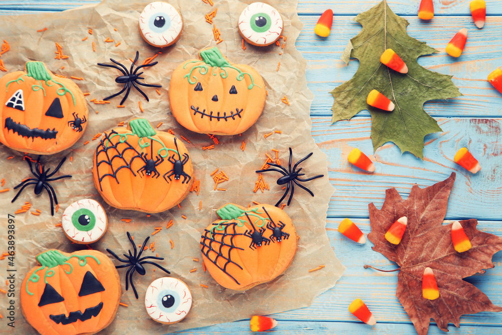 Halloween gingerbread cookies with candies, spiders and dry leafs on blue wooden table Halloween gingerbread cookies with candies, spiders and dry leafs on blue wooden table