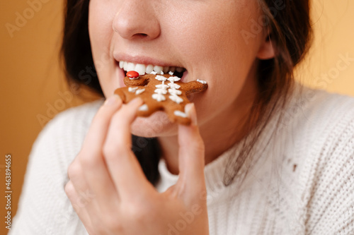 Close-up teeth biting off freshly baked gingerbread cookie for christmas. Healthy teeth and sweet concept.