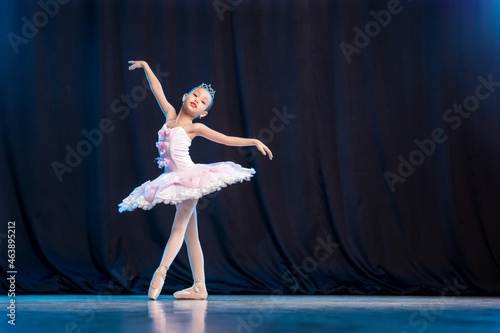 Fototapeta Naklejka Na Ścianę i Meble -  little girl ballerina is dancing on stage in white tutu on pointe shoes classic variation.