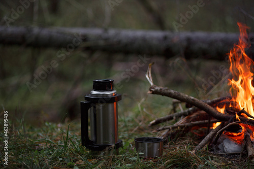 Thermos with a mug by the fire.