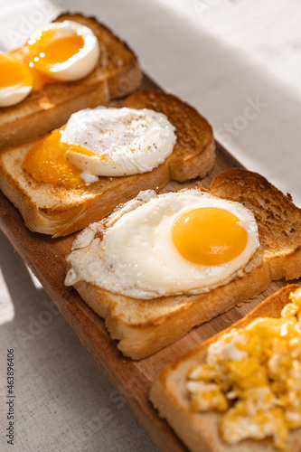 fried Toast bread with four different types of cooked chicken eggs, scrambled eggs, fried eggs, poached egg and creamed egg. Breakfast of chicken eggs. methods of making eggs for breakfast
