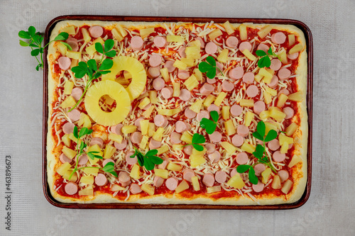 Hawaiian pizza with sausage and pineapple slices.