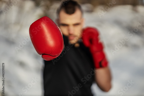 Closeup of boxer with boxing gloves standing in nature at snowy winter day and sparring. Selective focus on hand. Boxing in nature, healthy life, winter sport