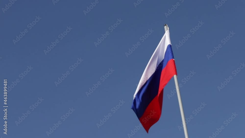 Russian flag on a flagpole on a blue sky background
