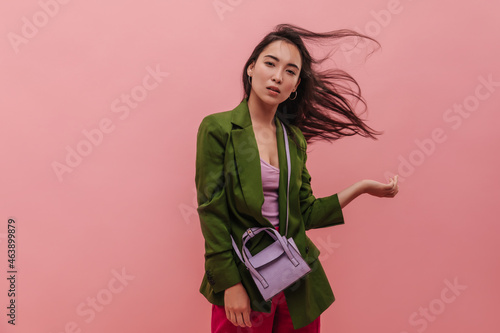 Fotografie Young fashionable asian woman playing with hair and looking deep into camera indoors
