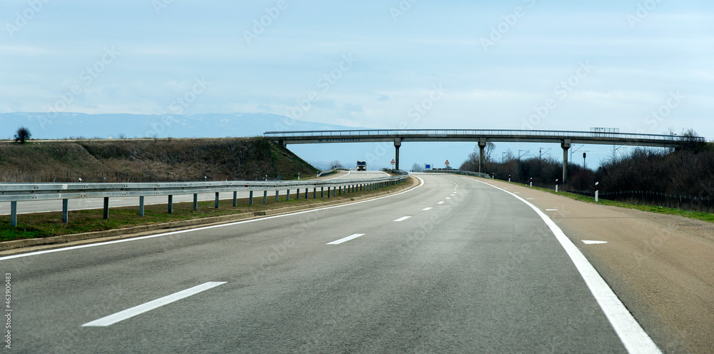 Fototapeta premium Road in the fog. Empty silent Freeway. Driving on an empty road. Empty asphalt road through the green field and clouds on rainstorm in rainy season. Open road ahead, endless road for concept.