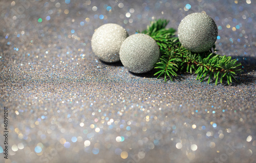 brokatowe bombki z iglastą gałązką na srebrnym brokatowym tle, świąteczne tło