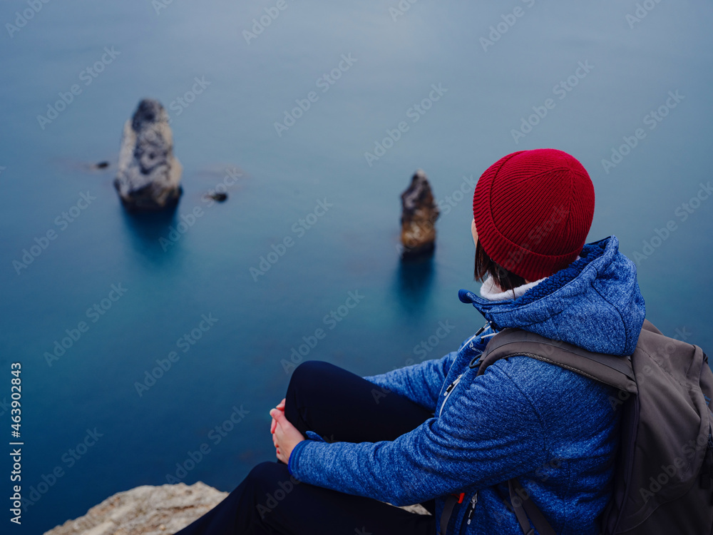 Back view of woman in blue jacket and hat on shore of North sea on cold winter day. Mood Scandinavian weather. travel adventure lifestyle idea and concept Back view of woman in blue jacket and hat on shore of North sea on cold winter day. Mood Scandinavian weather. travel adventure lifestyle idea and concept