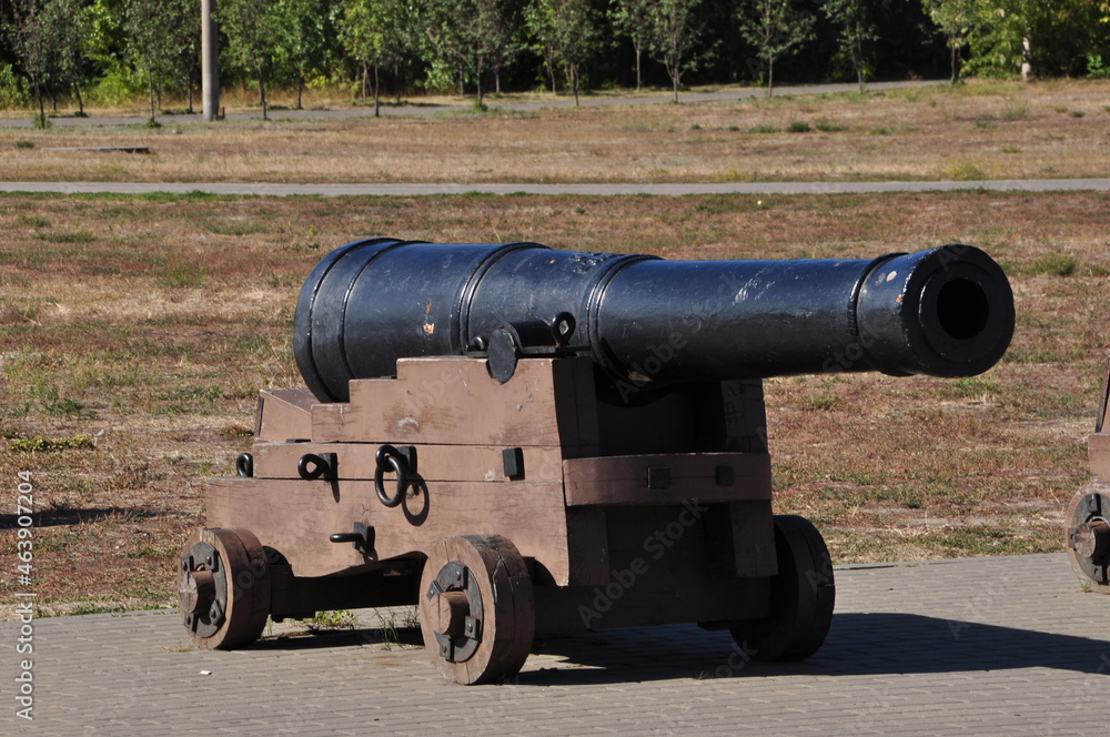 An old cast iron cannon. A cannon on a wooden gun carriage against the background of the road. Background.