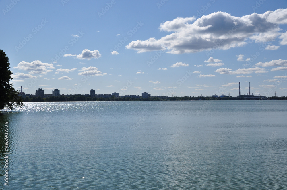 Panoramic view of the lake. Coastline with residential buildings and CHP pipes.