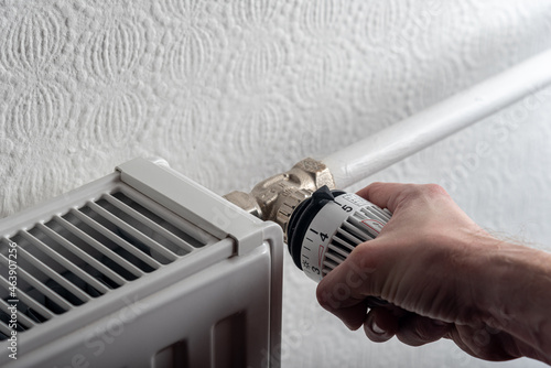 male hand turns the knob of the radiator to the highest level