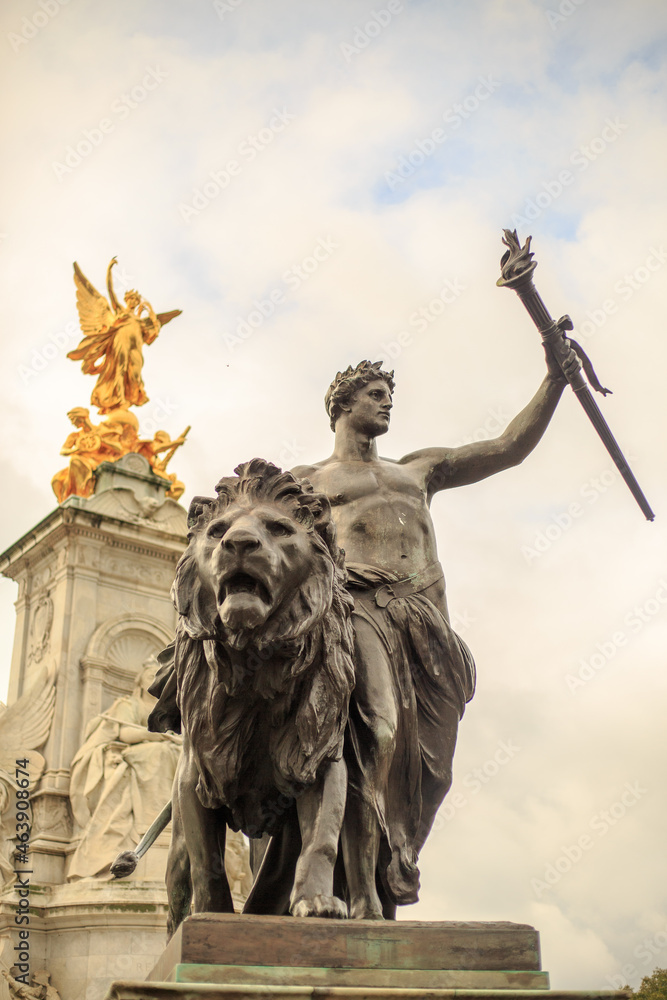 Fototapeta premium Queen Victoria Monument, London, 2021. The Progress statue is a youth, laurel-crowned, and bearing a torch in his left hand . Focus is on the sculpture infront of the memorial