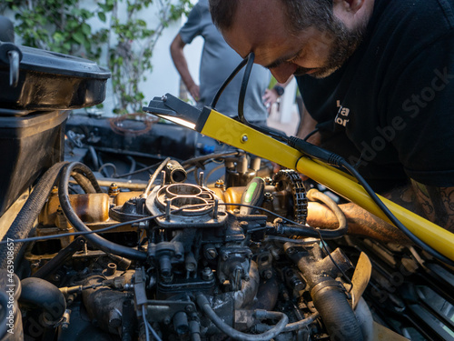 Mechanic repairing old engine with lighting