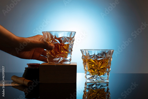Cognac or brandy on a glossy table on an isolated blue background