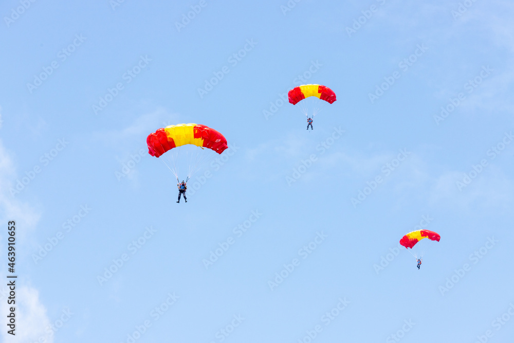 Skydivers under yellow and red parachute dome Skydivers under yellow and red parachute dome