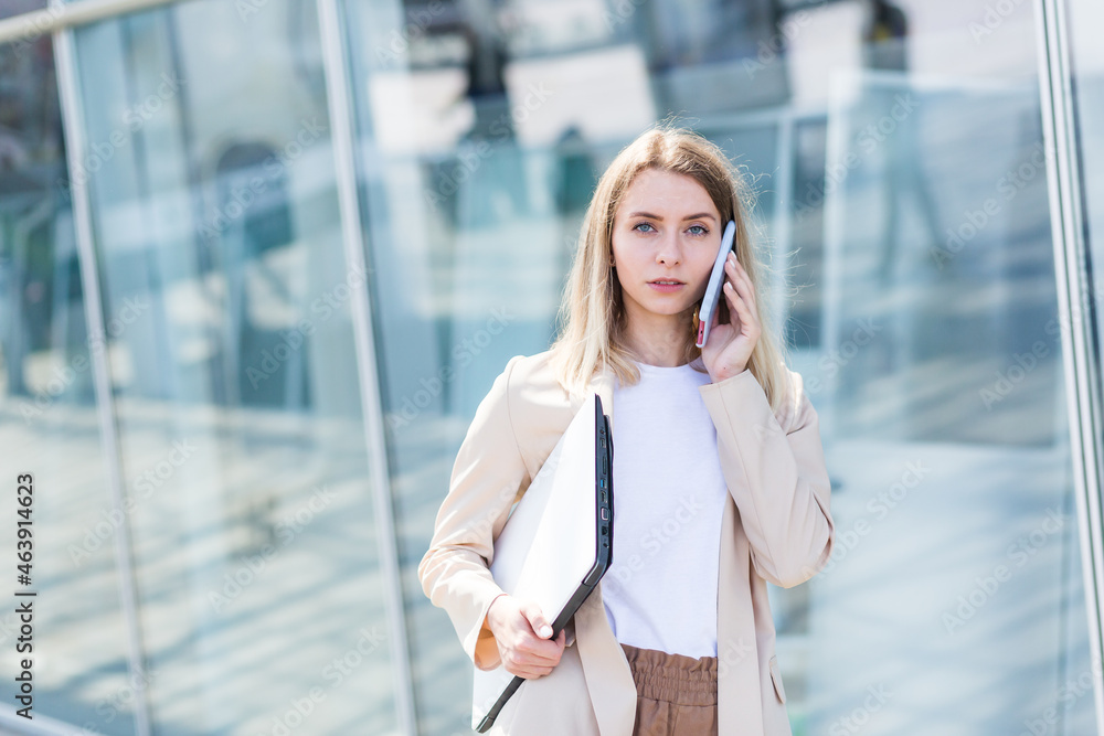 Young beautiful woman talking on a cell phone near the office, a businesswoman on a lunch break Young beautiful woman talking on a cell phone near the office, a businesswoman on a lunch break