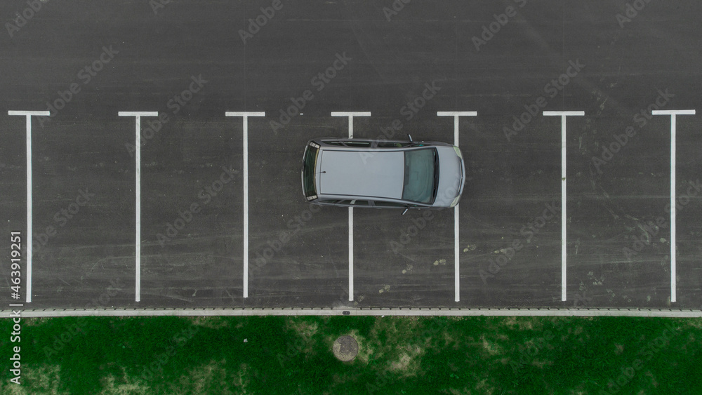 Stupid driver parking. A car parked over multiple parking spots. Car perpendicular to parking spots viewed from above. Aerial drone view of bad parking habit.