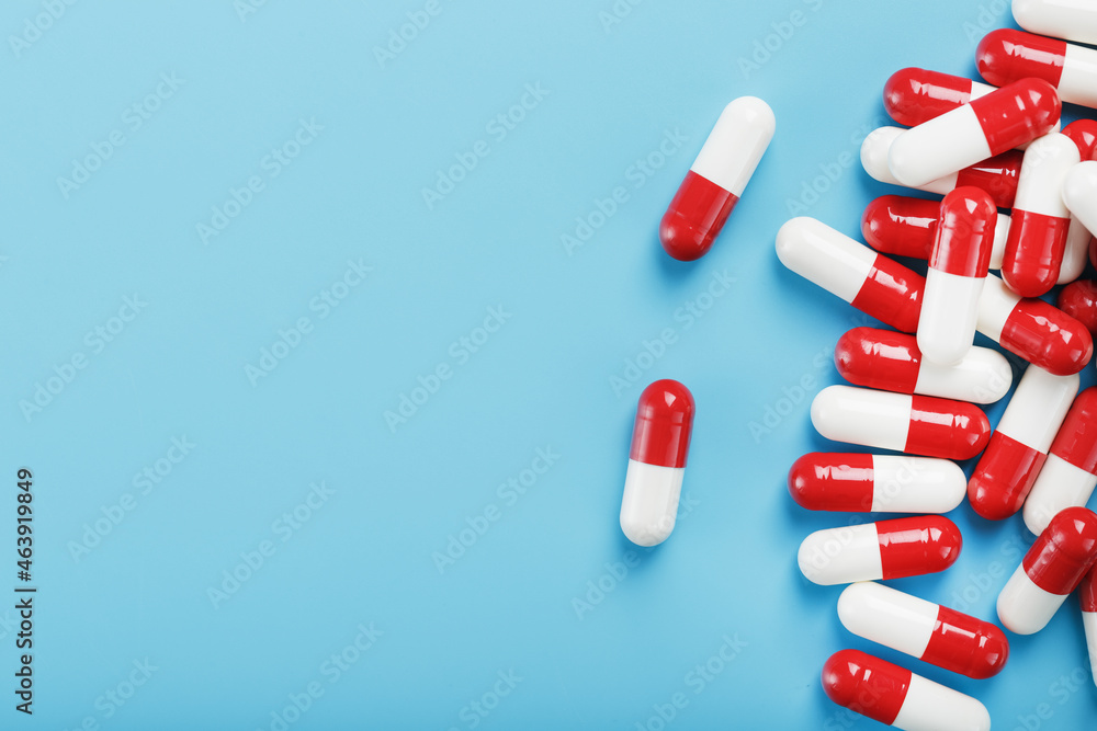 A handful of Red and white pill capsules on a blue background. Free space Top view A handful of Red and white pill capsules on a blue background. Free space Top view