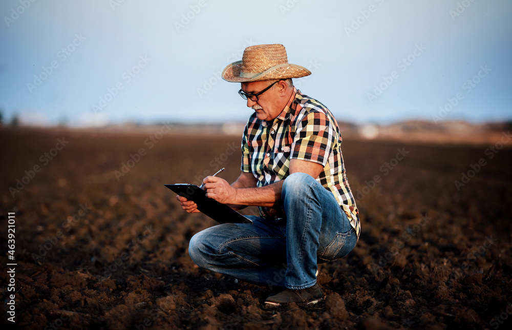 Farmer controls the soil and making a notes before sowing in the field. Agricultural concept Farmer controls the soil and making a notes before sowing in the field. Agricultural concept