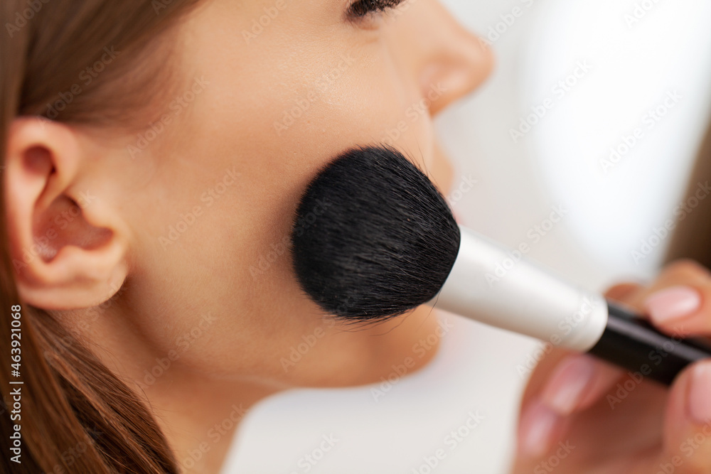 Young beautiful woman making make-up near mirror