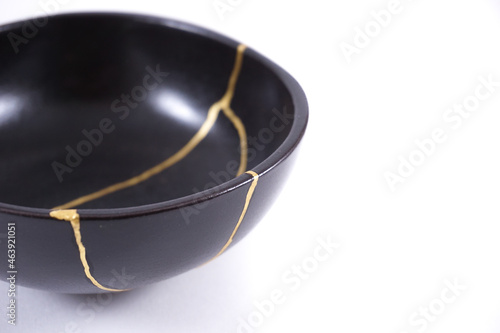 Isolated Japanese kintsugi black bowl restored with real gold , black pottery with gold cracks