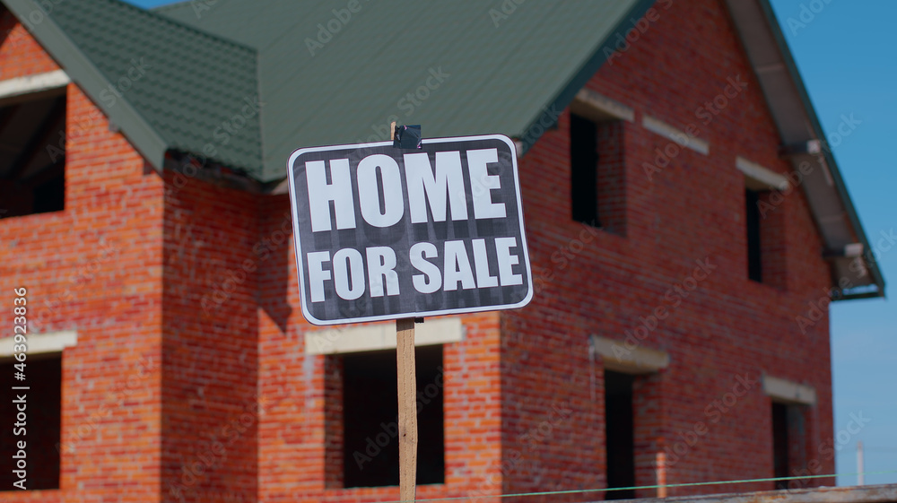 Fototapeta premium Home For Sale sign inscription note tag message on paper. For real estate company, buy and sell cheap house property, moving sign with house on background. Copy-space. Advertising. Selling apartment