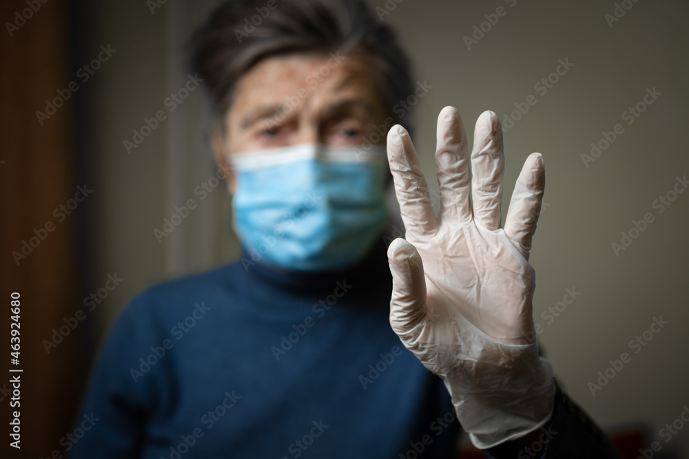 Importance wear gloves and masks to protect of coronavirus, especially elderly and seniors. Focus on latex gloves on background old woman in medical mask. Sign indicates protection against covid 19 Importance wear gloves and masks to protect of coronavirus, especially elderly and seniors. Focus on latex gloves on background old woman in medical mask. Sign indicates protection against covid 19