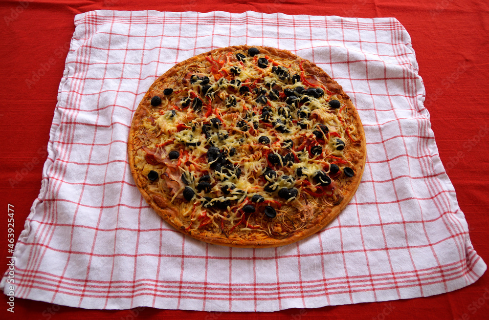 a delicious large home-made Italian pizza on a white kitchen towel a delicious large home-made Italian pizza on a white kitchen towel