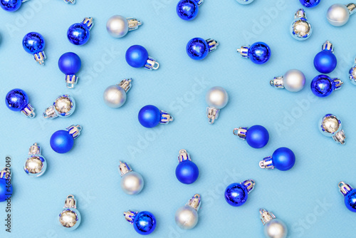 Blue and silver christmas decoration balls baubles on blue background with copy space. New year card. Minimalistic style. Flat lay.
