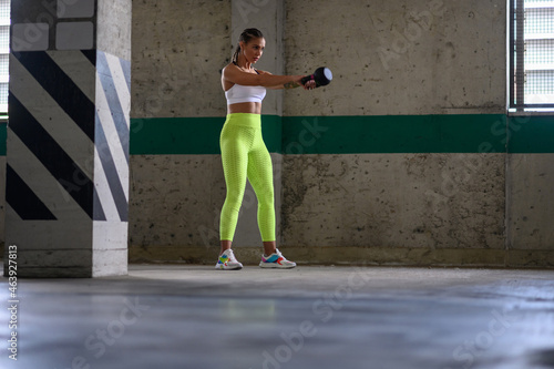 Young attractive woman training outside while using kettlebell