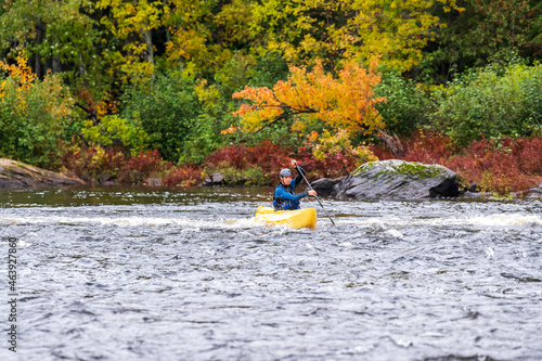A solo canoeist practices strokes on a rainy fall day during a “moving water” paddling course. Shot at Palmer Rapids on the Madawaska River an iconic paddling destination in Eastern Ontario, Canada