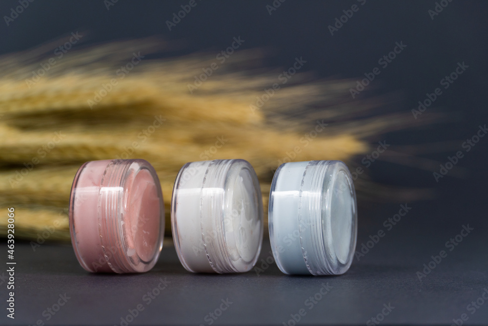 Face cosmetics. Facial creams of different colours on a grey background Face cosmetics. Facial creams of different colours on a grey background
