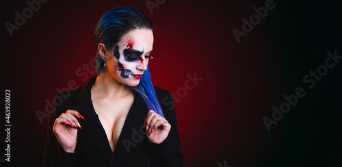 Woman with halloween style skull makeup with blue hair on red and black background