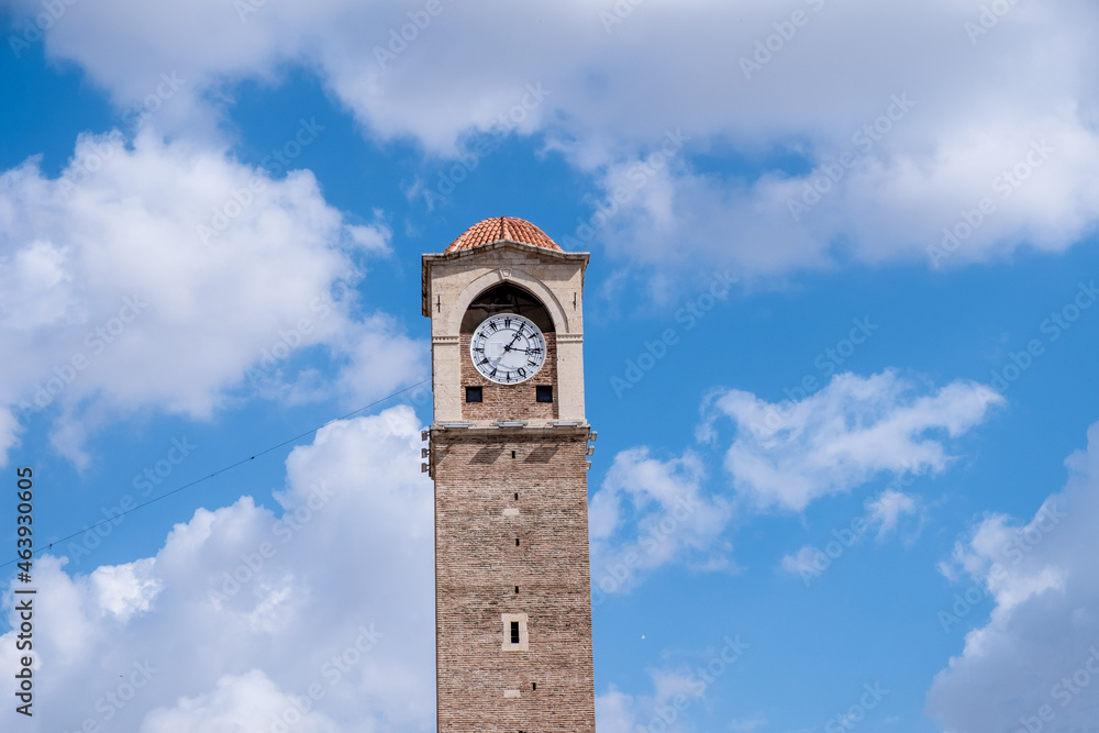 Old clock tower with blue and clouds sky in Adana, Turkey.