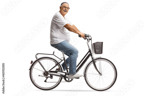 Smiling mature man in jeans and white t-shirt riding a bicycle