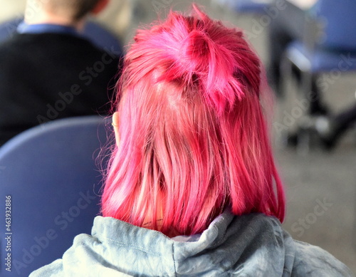Junge Frau im grauen Hoody mit rot gefärbten, schulterlangen Haaren