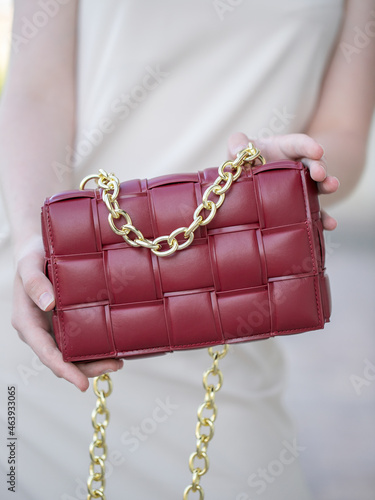 A woman's hand holds a red bag. Close-up. A woman on a walk. Business style, style element, accessory.