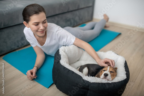 A young woman having a workout while her puppy sleeping near © zinkevych
