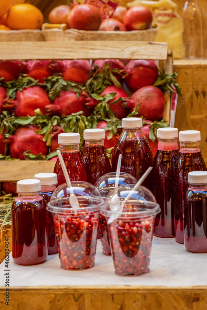 Sale of freshly squeezed juice and peeled juicy pomegranate seeds. Plastic bottles and glasses with natural vitamins Sale of freshly squeezed juice and peeled juicy pomegranate seeds. Plastic bottles and glasses with natural vitamins