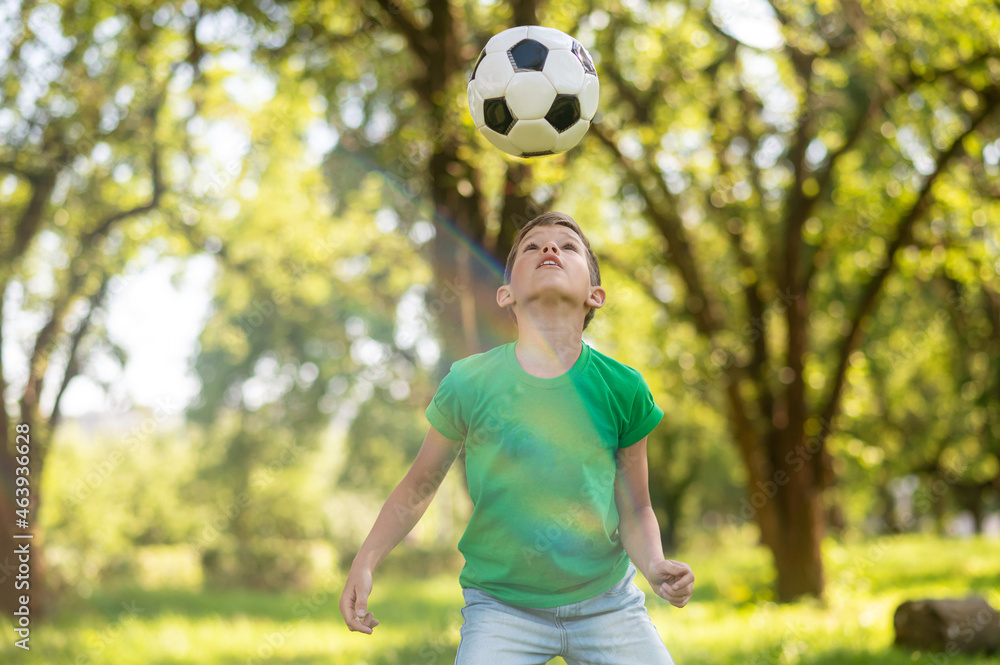Obraz premium Attentive boy looking at soccer ball up in air