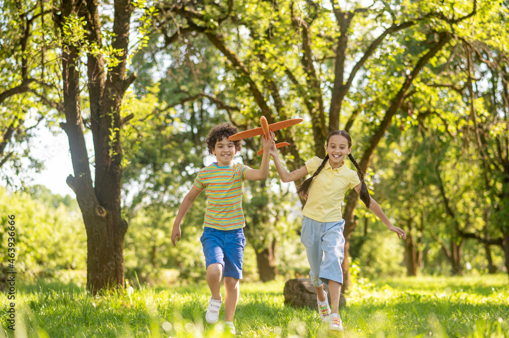 Boy and girl running with toy airplane Boy and girl running with toy airplane