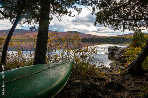A canoe perched along the lakeshore in Maine during peak foliage season. 