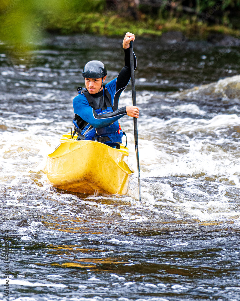 A solo canoeist practices on a rainy fall day during a “moving water” paddling course. Shot at Palmer Rapids on the Madawaska River an iconic paddling destination in Eastern Ontario, Canada