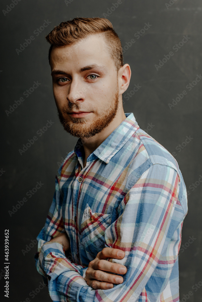 portrait of a young bearded man in shirt gray background
