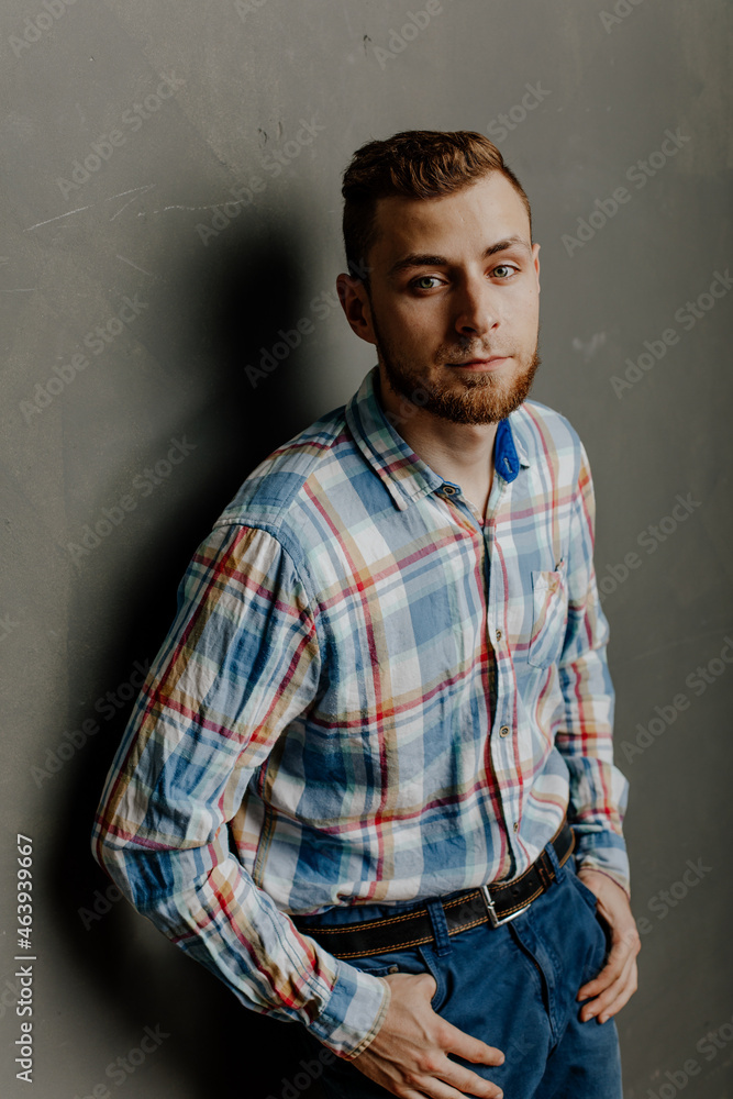portrait of a young bearded man in shirt gray background